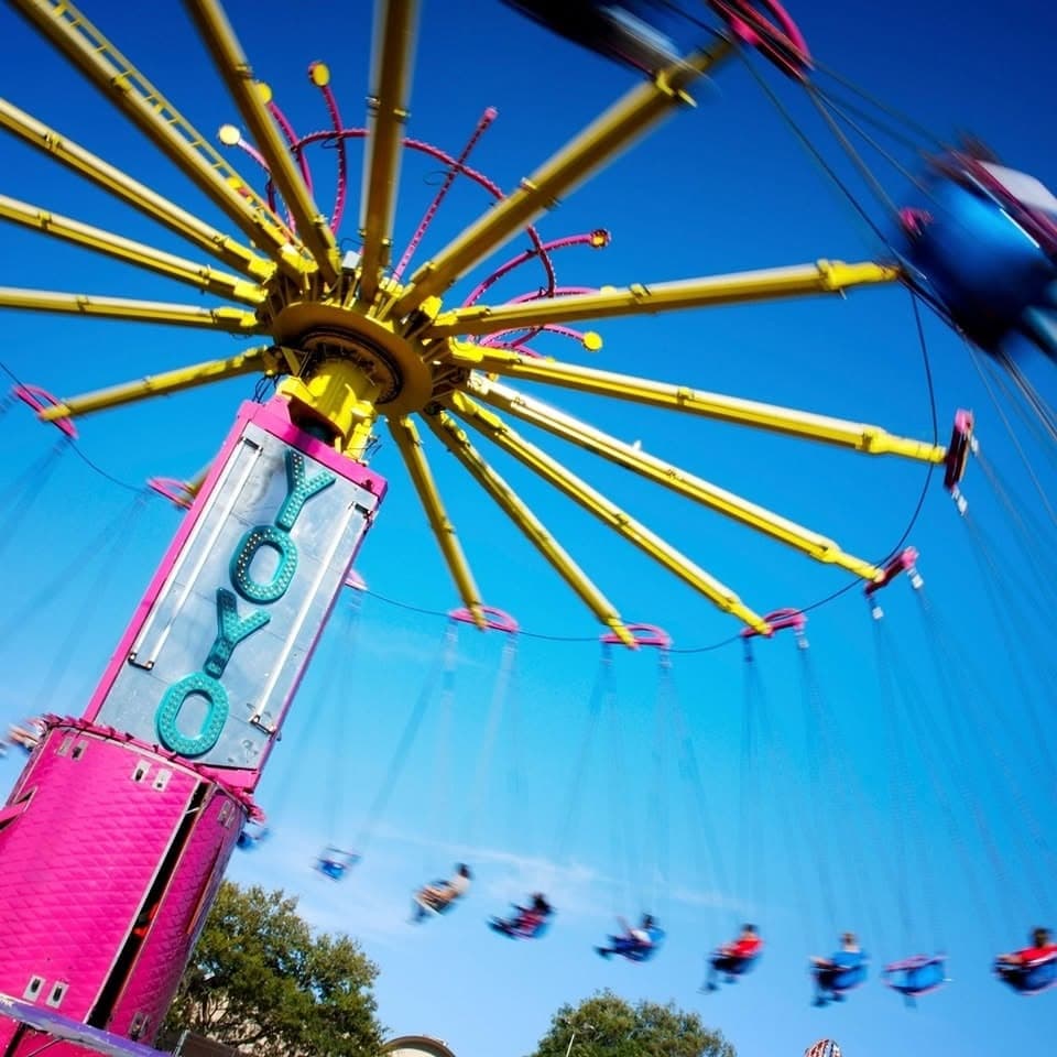 The YoYo swing carousel ride spinning riders against a bright blue sky